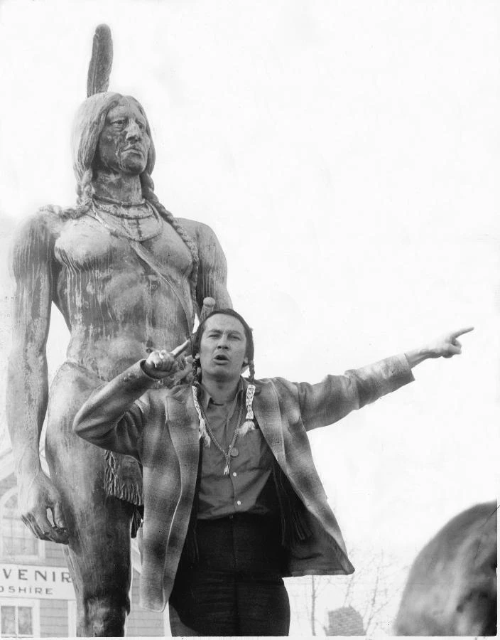 Russell Means in front of the statue of Massasoit